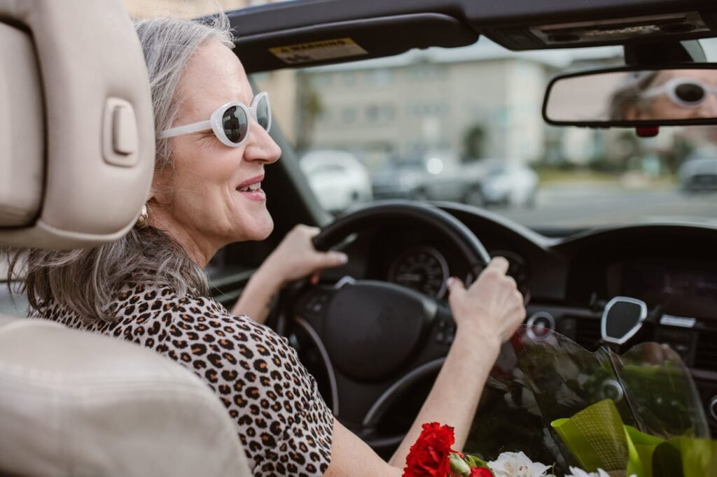 pexels photo 6540123 Senior woman driving a convertible, smiling and wearing sunglasses on a sunny day.