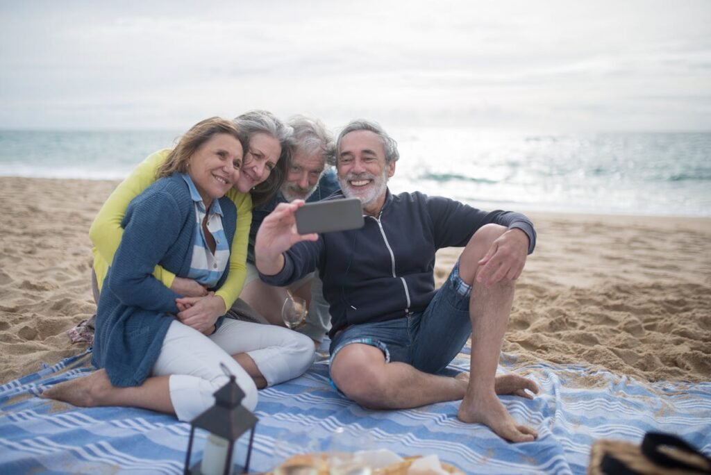 pexels photo 8170291 A joyful group of senior friends taking a selfie during a beach picnic by the ocean.